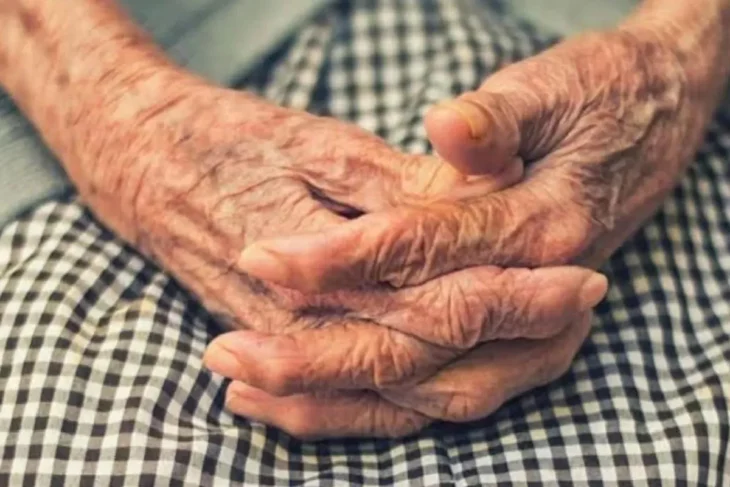 imagen de las manos de una ancianita las tiene puestas sobre su regazo y lleva un mandil