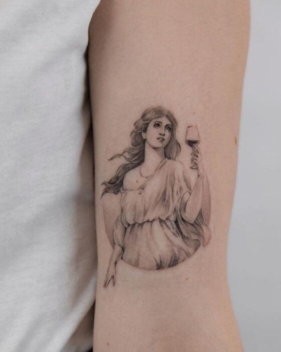 piel con un tatuaje con el diseño de la Diosa Deméter con una copa en su mano 