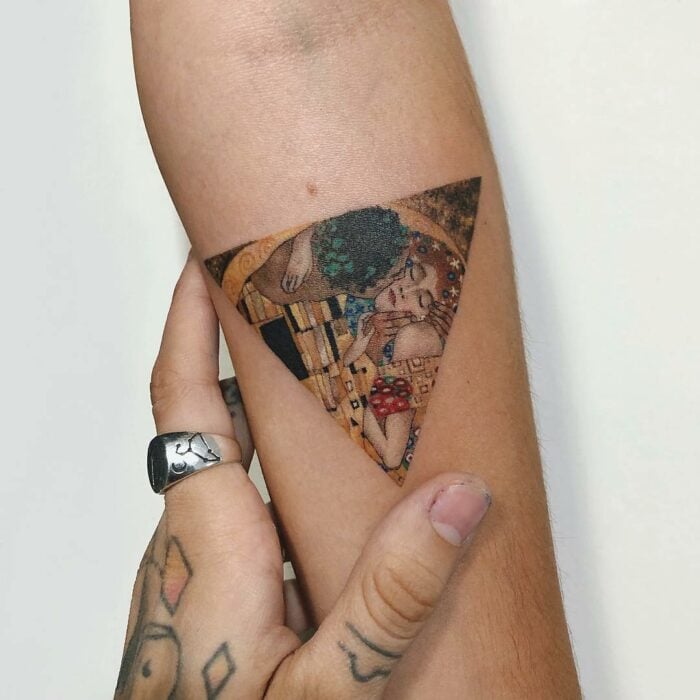 tatuaje en forma de triángulo con el diseño de la pintura de el beso de Gustav Klimt 