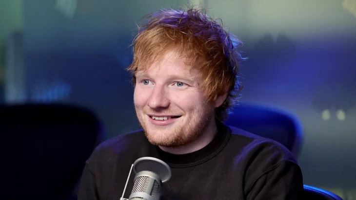 Ed Sheeran sonríe en una entrevista tiene un micrófono enfrente de él