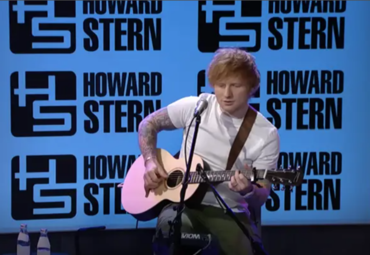 Ed Sheeran en una presentación con Howard Stern esta tocando la guitarra y cantando
