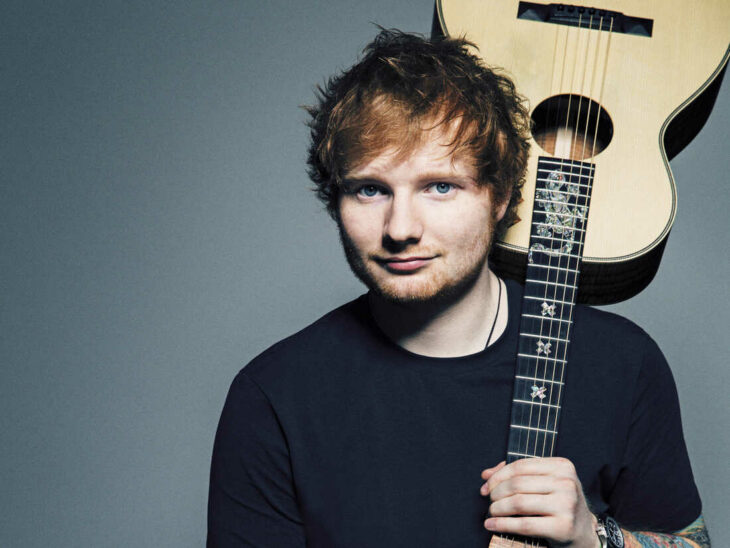 Ed Sheeran posa en una imagen sosteniendo su guitarra al revés y en su espalda 