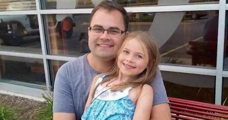 un padre con anteojos sonríe feliz con su hija en brazos la niña tiene alrededor de nueve años
