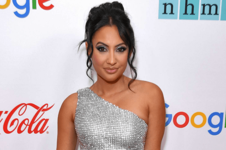 Francia Raisa poses on a red carpet in a silver dress