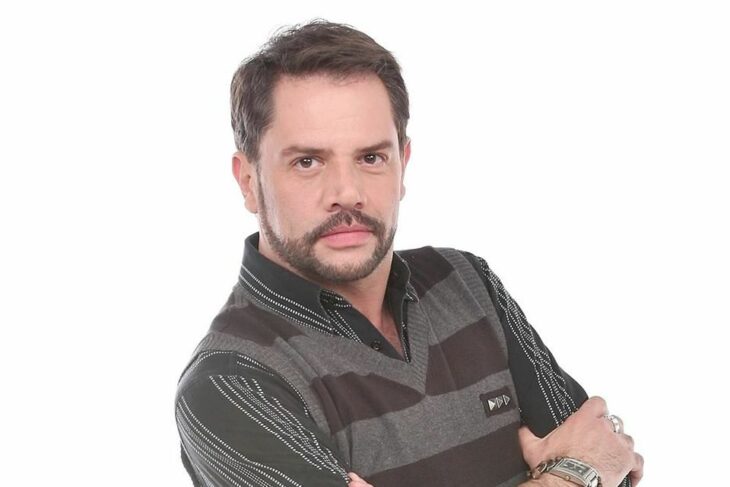 el actor Héctor Parra posa para la cámara con ropa semi formal tiene una expresión de seriedad 