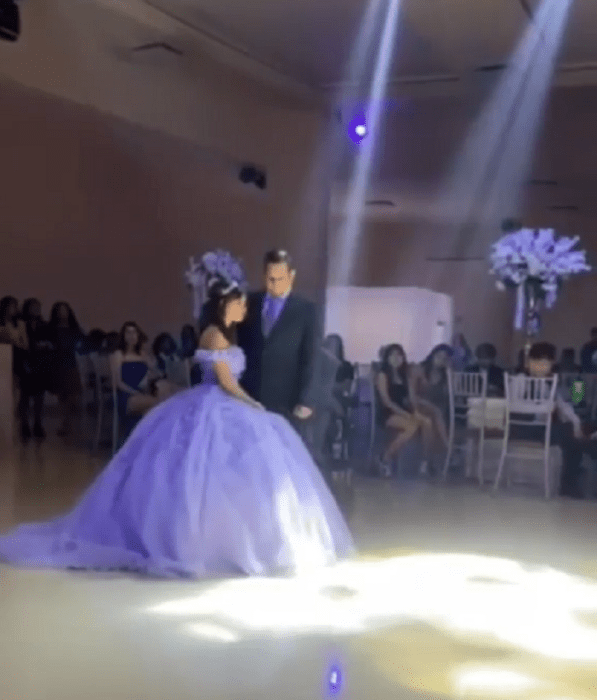 un papá esta parado junto a su hija en la fiesta de XV años van a iniciar el vals en la pista de baile