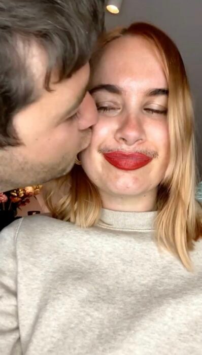 hombre dándole un beso a una mujer con bigote 