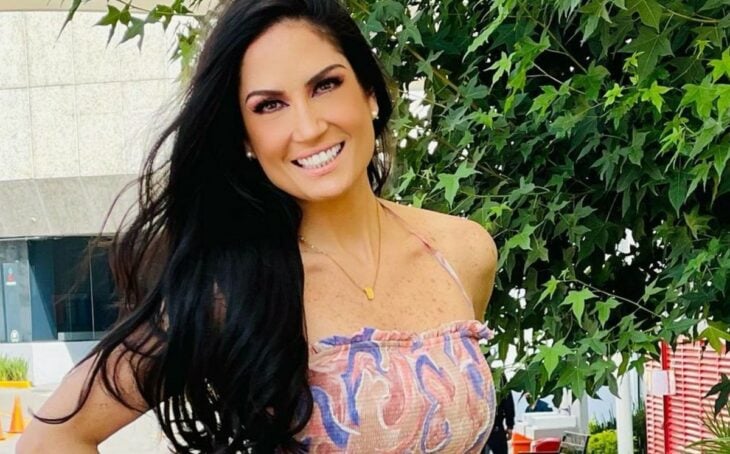 Joanna Vega-Biestro smiles in the image she is outside next to a very green tree