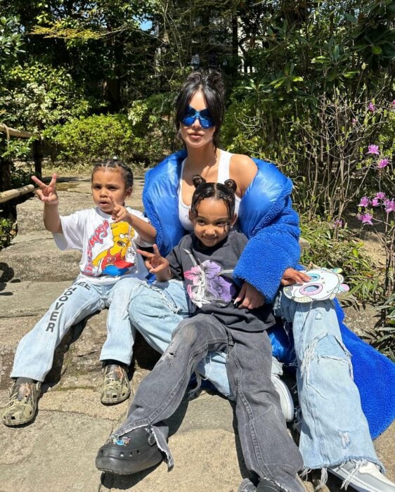 Kim Kardashian posando con dos de sus hijos sentados en el suelo 