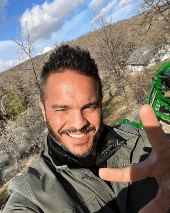 Kuno Becker saluda a la cámara con una sonrisa está al aire libre y lleva una chamarra gris