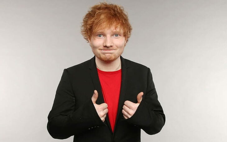 Ed Sheeran hace una mueca a la cámara mientras muestra sus pulgares arriba 