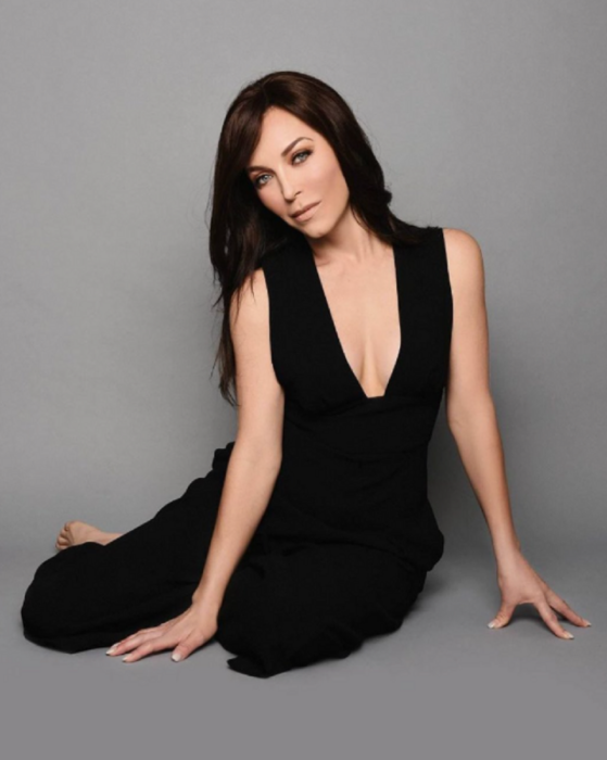 Laura Flores posando sentada en el piso vestida de negro