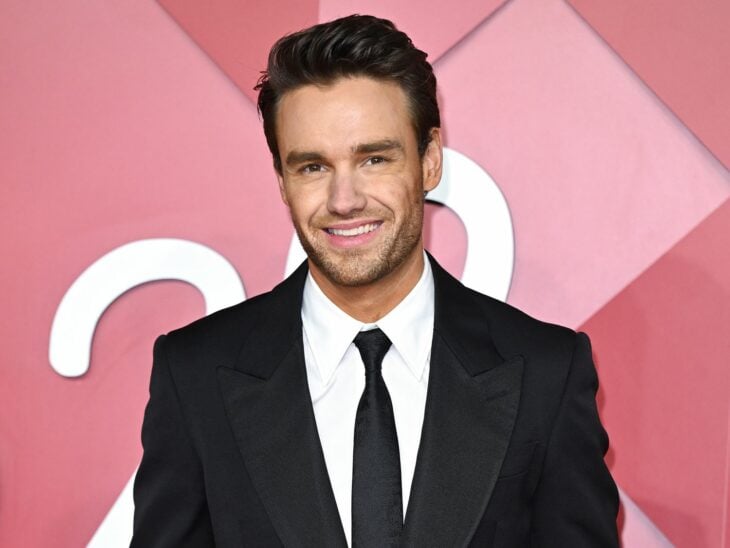 Liam Payne former One Direction member poses with a smile dressed formally in a dark suit