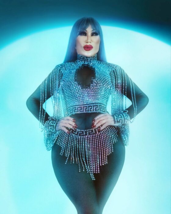 Lyn May posing on a blue background 