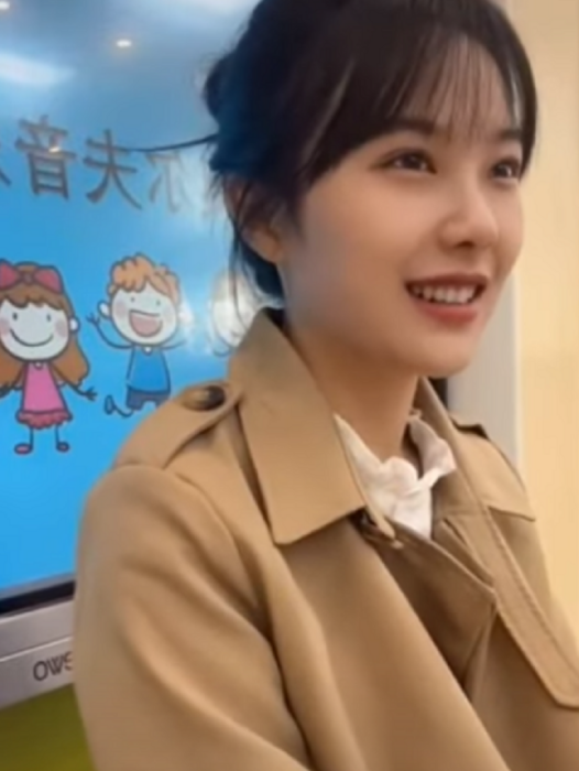 una maestra de kínder china en un salón de clases lleva el cabello recogido y un saco color cameo