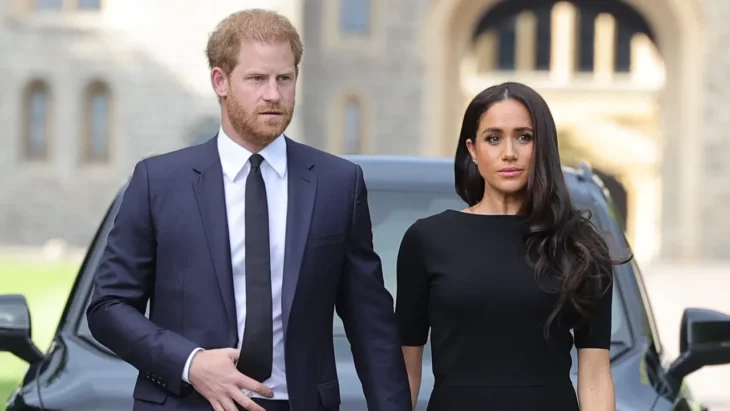 Meghan y Harry tienen expresiones de preocupación en su rostro caminan tomados de la mano