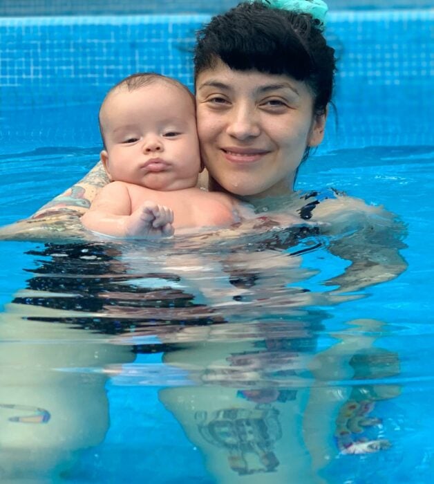 Mon Laferte cargando a su hijo dentro de una piscina