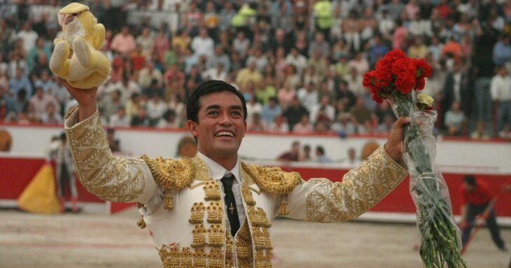 El torero Rafael Ortega saludando a la afición en el ruedo de una Plaza de Toros lleva un ramo de rosas en la mano y un peluche 