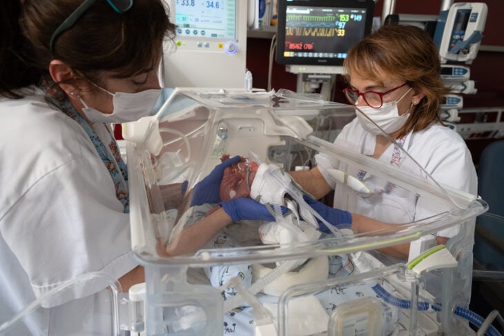 enfermeras en un hospital viendo a un bebé dentro de una incubadora 