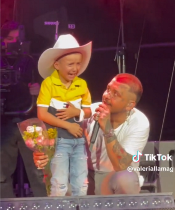 El cantante Christian Nodal mira con asombro a un niño que invitó al escenario quien no para de llorar