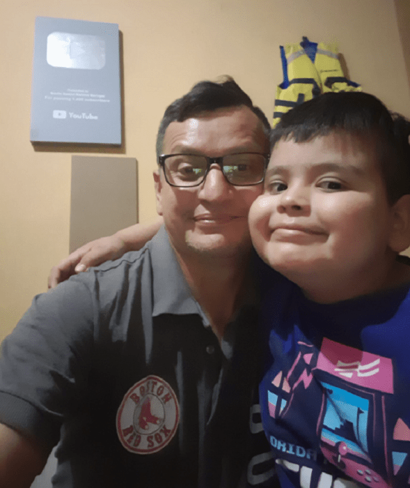 un niño abraza cariñoso a su papá quien lleva anteojos están en una habitación 