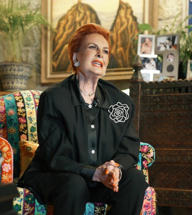 Talina Fernández con traje negreo sentada en un sofá 