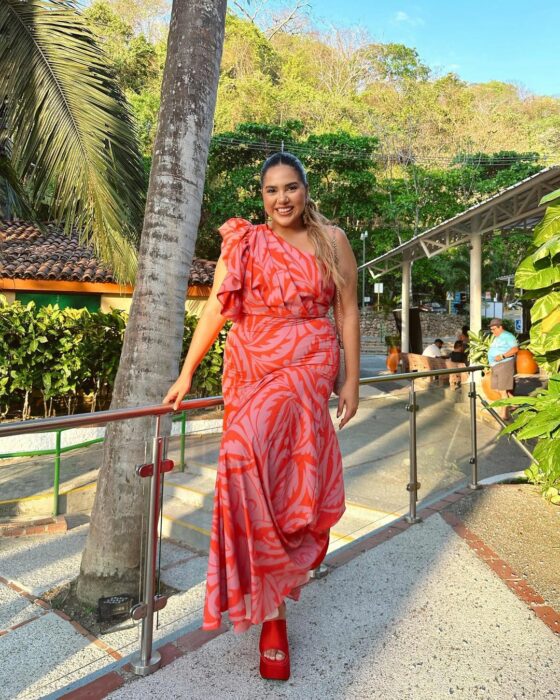 Jessi Rodriguez con vestido rojo recargada en un barandal 