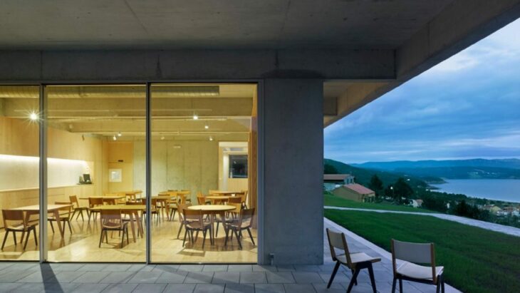 Imagen exterior de un restaurante con ventanales de cristal que está en medio de un monte