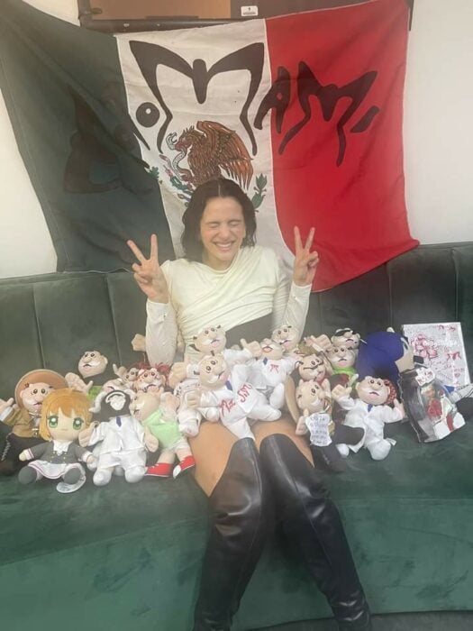 Rosalía posando con muchos simis sentada en un sillón con la bandera de México de fondo 