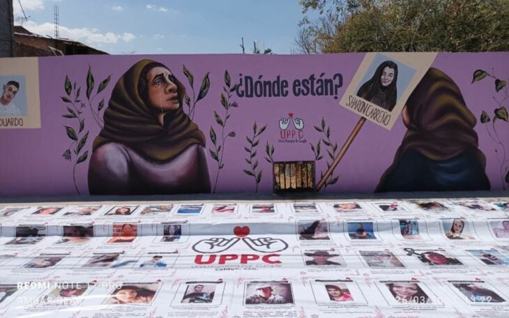 imagen del colectivo de madres buscadoras Una promesa por cumplir donde aparecen imágenes de los desaparecidos y la pintura de una mujer con reboso sobre la pared