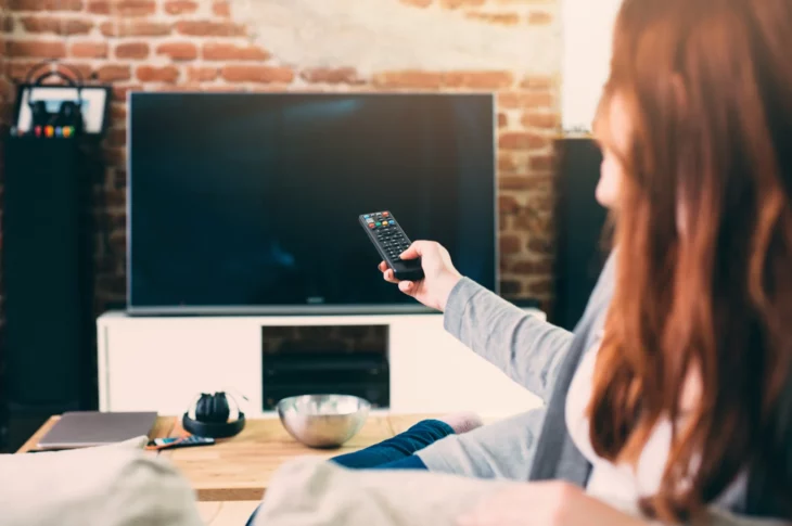 Chica pelirroja encendiendo el televisor