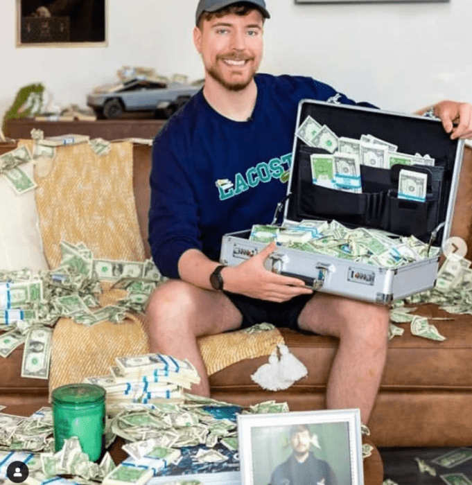 Jimmy Donaldson, mejor conocido como MrBeast posa en un sillón con un portafolio lleno de dólares y rodeado de billetes por todos lados