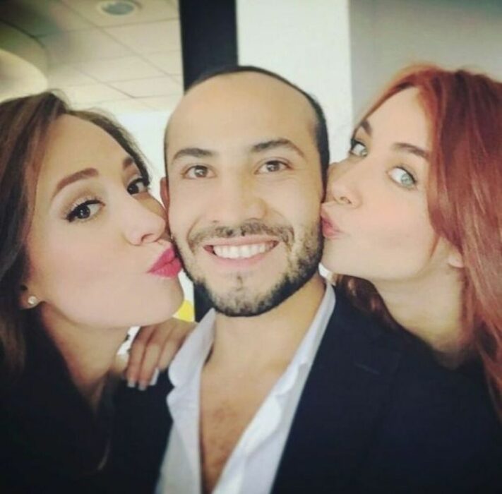 Mickey Santana con dos chicas besándole las mejillas 