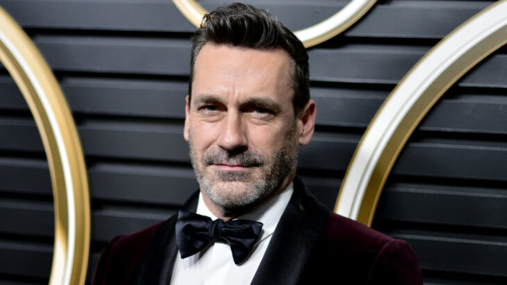 Jon Hamm posa con esmoquin guinda oscuro y un moñito azul marino lleva la barba y el bigote muy visibles