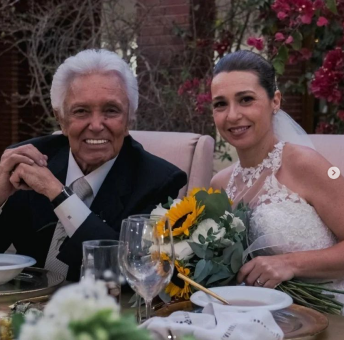 Alberto Vázquez y su esposa posan en la mesa de honor de su boda ella lleva aun su ramo en las manos 