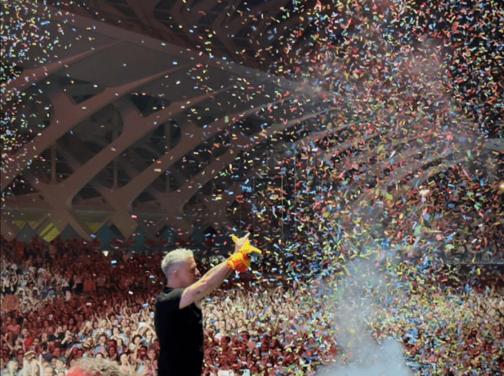 The singer Alejandro Sanz standing on stage while a rain of colored pieces of paper falls
