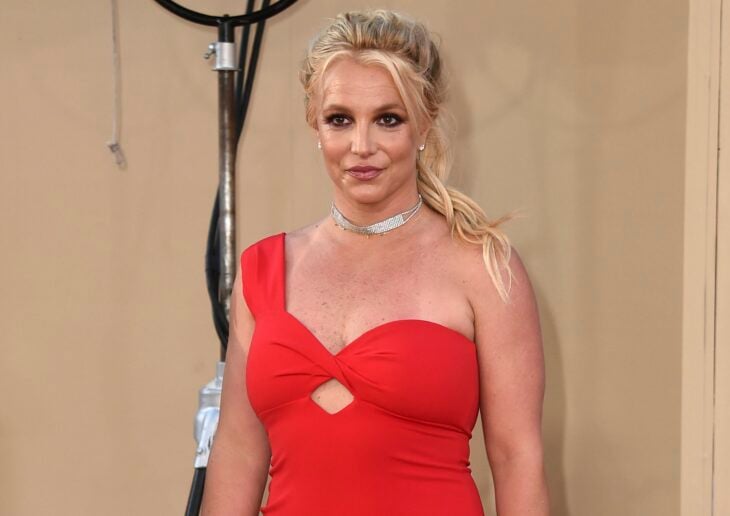 Britney Spears posa con un vestido de coctel de color rojo lleva el cabello recogido en una coleta despeinada