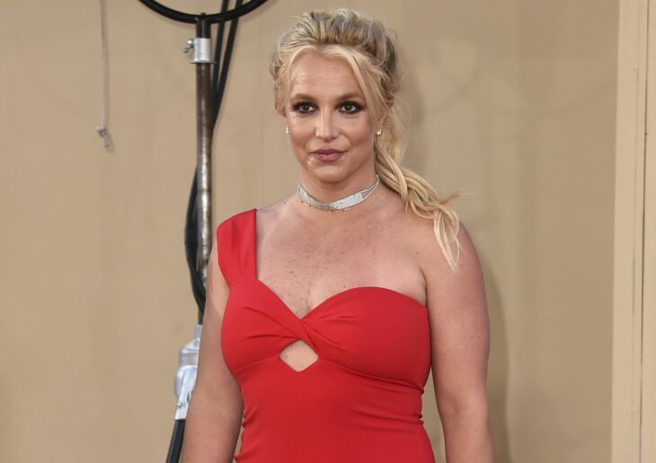 Britney Spears posa con un vestido de coctel de color rojo lleva el cabello recogido en una coleta despeinada