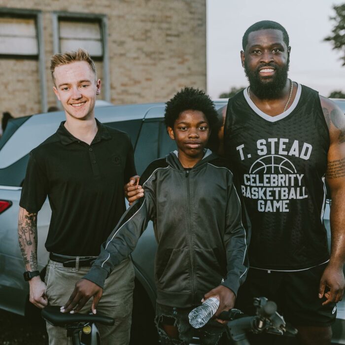 Chico en medio del atleta Terron Armstead quien le regaló una bicicleta eléctrica 