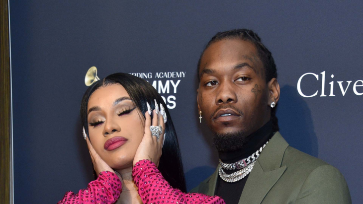 Cardi B y Offset posando en una alfombra roja ella cierra los ojos y se lleva las manos a los oídos como si mostrara que no quiere ver ni escuchar él mira a un lado de la cámara con semblante serio