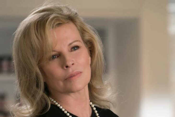 Kim Basinger posa en la escena de alguna película lleva el cabello suelto peinado en ondas y un collar de perlas 