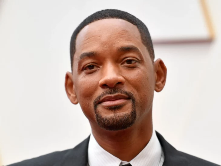 Will Smith posa con una mueca de sonrisa lleva un traje oscuro 