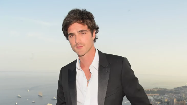 Jacob Elordi posa en una terraza junto al mar lleva un saco con camisa pero sin corbata