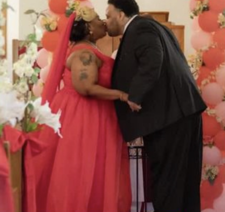 unos novios se besan al final de su ceremonia religiosa ella porta un vestido largo de color rojo