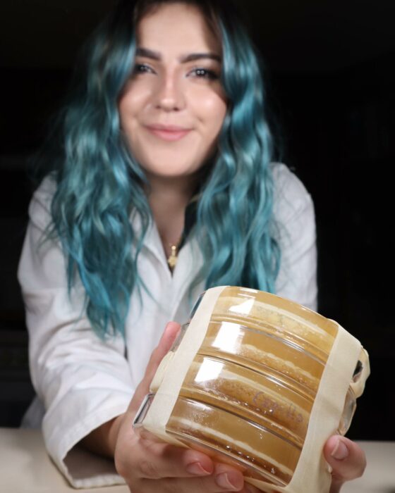 Fotografía de una chica de cabello azul mostrando unos cultivos 