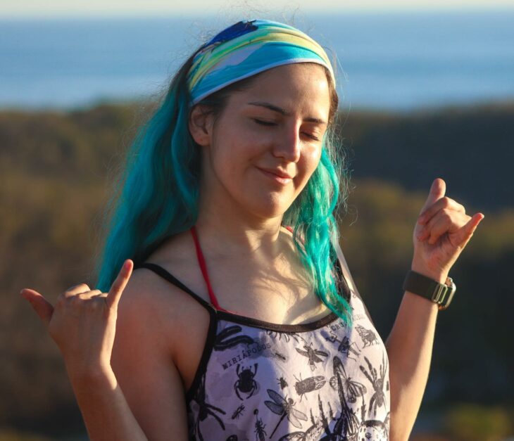 Fotografía de una chica de cabello azul frente a un paisaje de montañas 