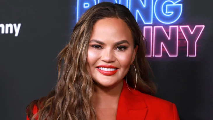 Chrissy Teigen smiles posing on a television show