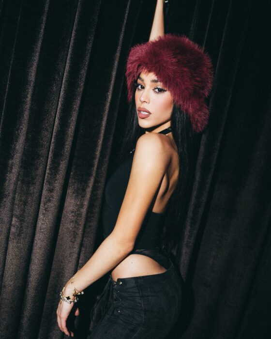 Fotografía de Danna Paola posando vestida de negro con un gorro rojo en la cabeza 