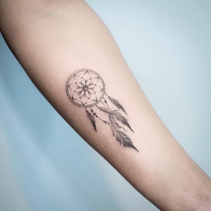 Tatuaje con el diseño de un atrapasueños en el antebrazo de una persona 