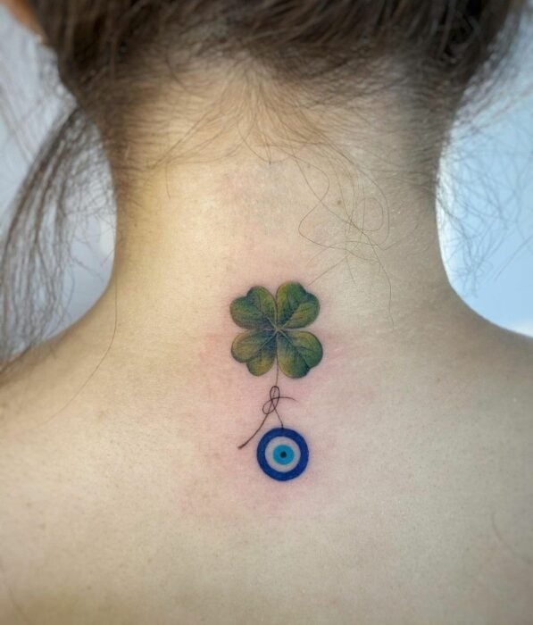 Tatuaje de un ojo turco con un trébol de cuatro hojas en la nuca de una chica 